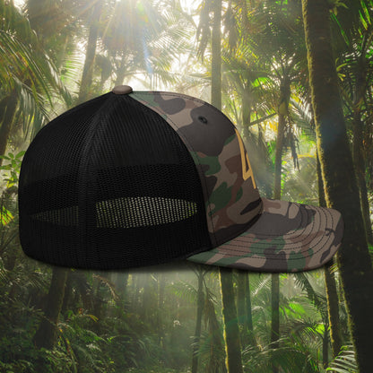 Camouflage and black mesh cap against a tropical forest background